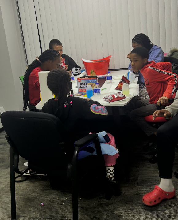 Momentum Youth Group members gathered around a table sharing snacks and conversation during a group session.